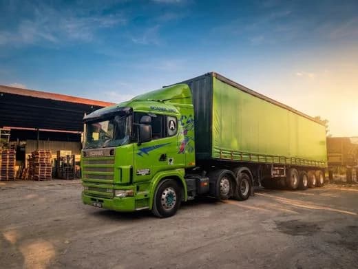 The same Scania and curtain-side combination photographed from the yard, timber racks stacked behind it
