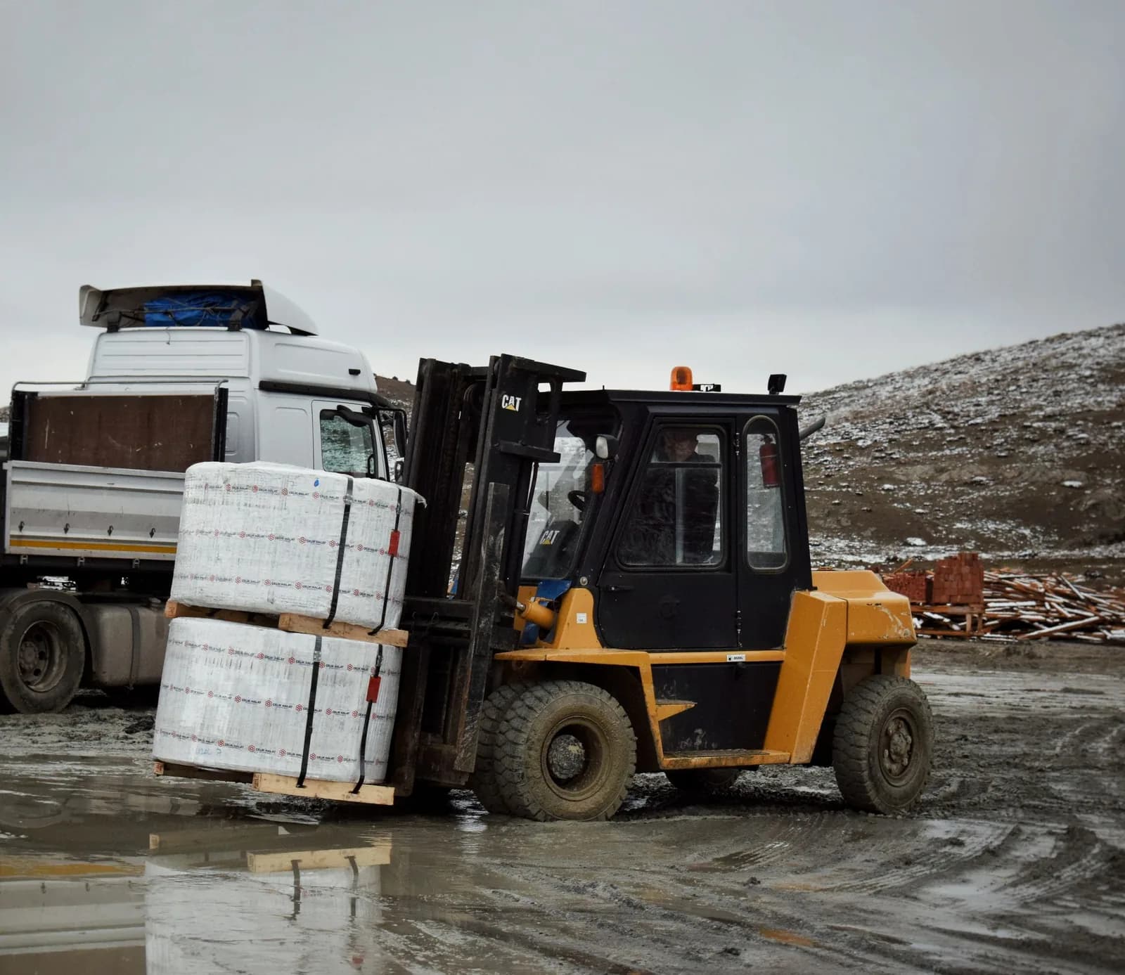 A counterbalance forklift with its forks lowered in a yard.