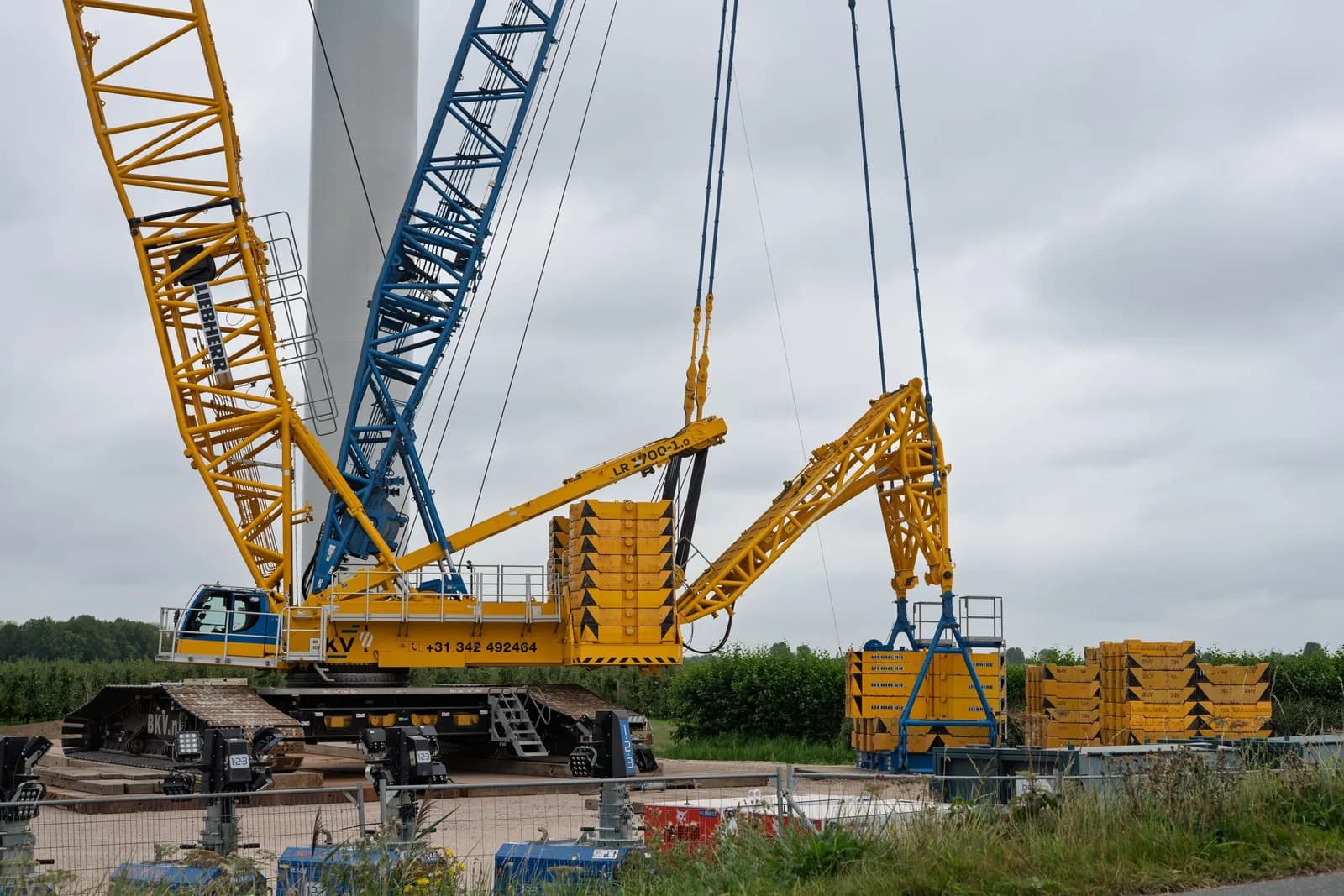 A large lattice-boom crawler crane rigged on a construction site.